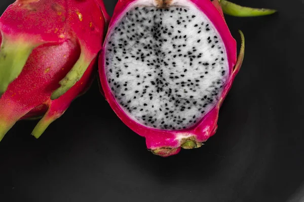 Drakfrukt. Vibrerande drake frukt på svart bakgrund. Skivad vit drake frukt eller pitaya på svart tallrik på bordet, närbild. Tropiska och exotiska frukter. Friska och vitamin livsmedel koncept. — Stockfoto