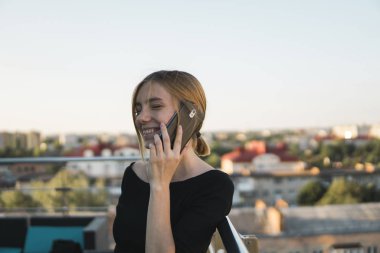 Genç bir iş kadını ofis binasının dışında akıllı cep telefonu kullanıyor ve iş ortaklarıyla konuşuyor. İş kadını telefona gülümseyerek cevap veriyor, iyi haberler alıyor. Serbest Çalışan.