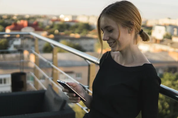 Young business woman uses phone. Good looking brunette female uses online banking on smart phone to transfer money from credit card. Girl using smart phone and chatting with business partners.