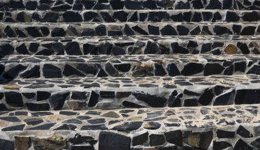 Stone stairs on the street made of black stones and gray cement.