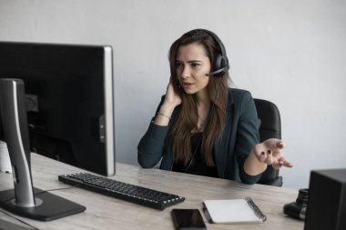 Genç Esmer kadın servis operatörü ofisi arıyor. Genç müşteri destek müdürü, tüketiciye kulaklıkla danışarak soruları yanıtlıyor.