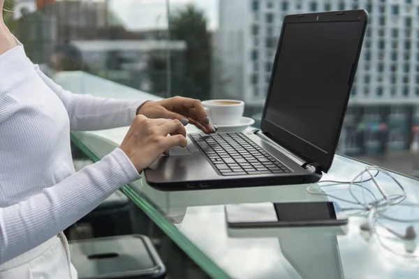 Una mujer está trabajando mediante el uso de una computadora portátil en la mesa. Manos escribiendo en un teclado. Mujer hombre de negocios está escribiendo en un teclado portátil sentado en la cafetería . — Foto de Stock