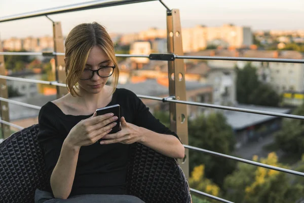 Young business woman uses phone. Good looking brunette female uses online banking on smart phone to transfer money from credit card. Girl using smart phone and chatting with business partners.