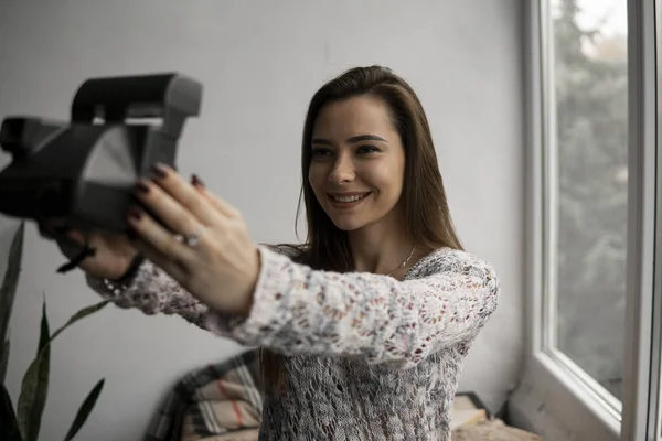 Smiling young brunette woman takes photographs selfie portrait with old photo camera. — Stock Photo, Image