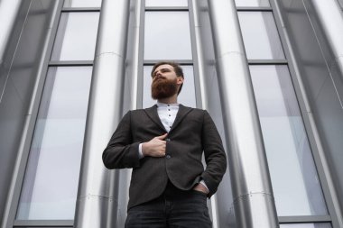 Finans bölgesindeki ofis binasında ceketli yakışıklı bir işadamının portresi. Genç sakallı iş adamı. Resmi giyinmiş başarılı bir girişimci..