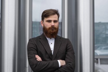 Finans bölgesindeki ofis binasında ceketli yakışıklı bir işadamının portresi. Genç sakallı iş adamı. Resmi giyinmiş başarılı bir girişimci..