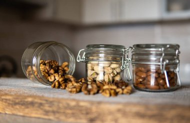 Ceviz bir kavanozdan beyaz şarap masasına saçılmış. Ceviz sağlıklı bir vejetaryen protein besleyici gıdadır. Ceviz çekirdekleri ve eski ahşap cevizler..