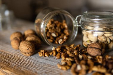 Ceviz, bir kavanozun içindeki beyaz şarap masasına serpilmişti. Ceviz sağlıklı bir vejetaryen protein besleyici gıdadır. Ceviz çekirdekleri ve eski ahşap cevizler..