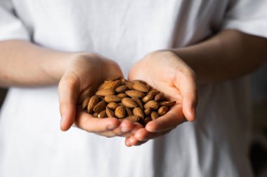 Bir kadının elinde badem. Badem fıstığı sağlıklı bir vejetaryen proteini ve besleyici yemektir. Bir insanın elinde fındık.