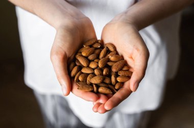 Bir kadının elinde badem. Badem fıstığı sağlıklı bir vejetaryen proteini ve besleyici yemektir. Bir insanın elinde fındık.