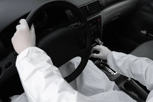 保護スーツの男、細菌やウイルスから身を守るための医療用マスクとゴム手袋は車を運転しています。隔離中の保護マスク世界的大流行covid 19コロナウイルス感染. — ストック写真
