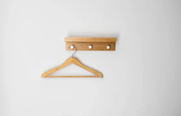 Ρούχα ξύλινη κρεμάστρα σε λευκό τοίχο. — Φωτογραφία Αρχείου