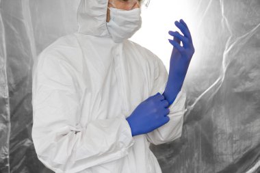 Beyaz koruyucu giysili, maskeli, gözlüklü ve lastik eldivenli doktor koronavirüs salgını tehdidi altındaki insanlara yardım etmeye hazır. Salgın, Coronavirus covid 19 salgını. Solunum cihazındaki doktor..