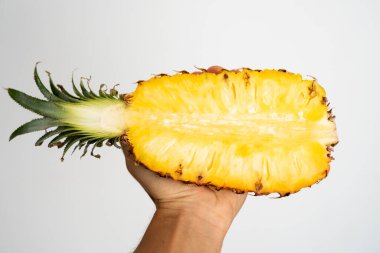 Beyaz arka planda olgun ananasın yarısını tutan bir kadın..