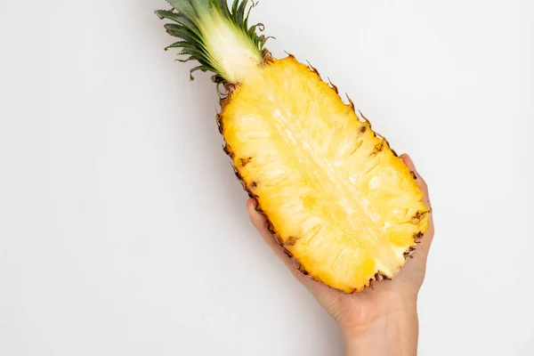 Female hand holding a half of ripe pineapple on a white background. — Stock Photo, Image