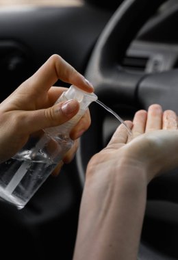 Kadın araba sürmeyi planlarken kendini bakteri virüsünden korumak için antiseptik kullanıyor. Karantina, pandemik, covid 19, koronavirüs, enfeksiyon....