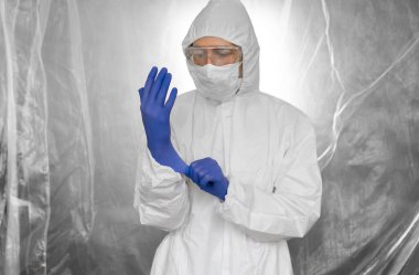 Beyaz koruyucu giysili, maskeli, gözlüklü ve lastik eldivenli doktor koronavirüs salgını tehdidi altındaki insanlara yardım etmeye hazır. Salgın, Coronavirus covid 19 salgını. Solunum cihazındaki doktor..