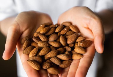 Bir kadının elinde badem. Badem fıstığı sağlıklı bir vejetaryen proteini ve besleyici yemektir. Bir insanın elinde fındık.