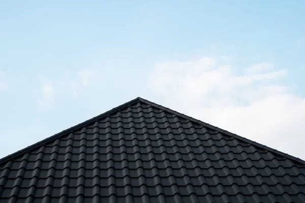 Μαύρη μεταλλική κεραμοσκεπή. Μεταλλικά φύλλα οροφής. Σύγχρονοι τύποι υλικών στέγης. Στέγη του σπιτιού, μεταλλικό κεραμίδι στον γαλάζιο ουρανό. Κτήριο. — Φωτογραφία Αρχείου