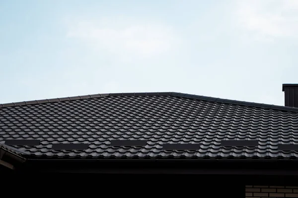 Brązowy dach metalowy. Blachy dachowe. Nowoczesne rodzaje materiałów dachowych. Dach domu, dach metalowy dachówka na tle błękitnego nieba. Budowa. — Zdjęcie stockowe