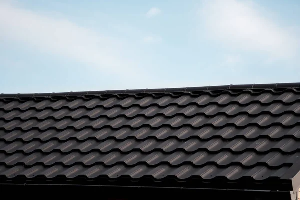 Καφέ μεταλλική κεραμοσκεπή. Μεταλλικά φύλλα οροφής. Σύγχρονοι τύποι υλικών στέγης. Στέγη του σπιτιού, μεταλλικό κεραμίδι στον γαλάζιο ουρανό. Κτήριο. — Φωτογραφία Αρχείου