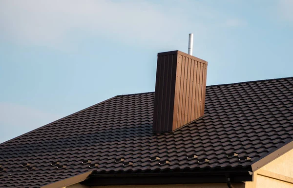 갈색 금속 타일 지붕. 금속 판이야. 현대적 인 종류의 지붕 재료. 집의 지붕 과파란 하늘을 배경으로 한 금속 타일이었습니다. 건축. — 스톡 사진