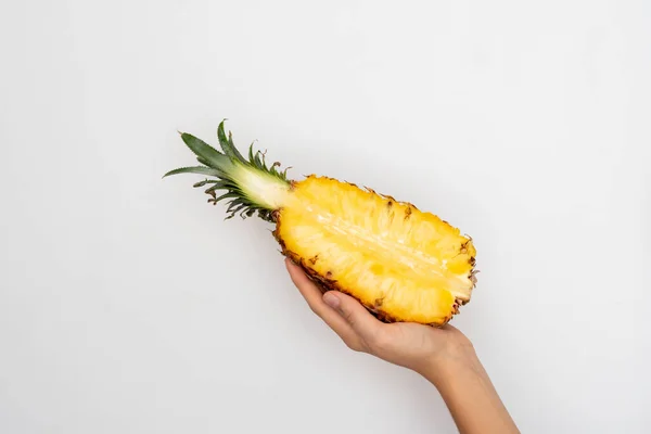 Weibliche Hand hält eine Hälfte reife Ananas auf weißem Hintergrund. — Stockfoto