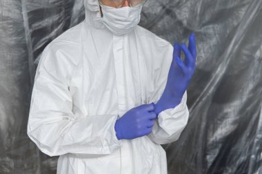 Beyaz koruyucu giysili, maskeli, gözlüklü ve lastik eldivenli doktor koronavirüs salgını tehdidi altındaki insanlara yardım etmeye hazır. Salgın, Coronavirus covid 19 salgını. Solunum cihazındaki doktor..