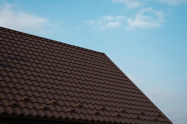 갈색 금속 타일 지붕. 금속 판이야. 현대적 인 종류의 지붕 재료. 집의 지붕 과파란 하늘을 배경으로 한 금속 타일이었습니다. 건축. — 스톡 사진