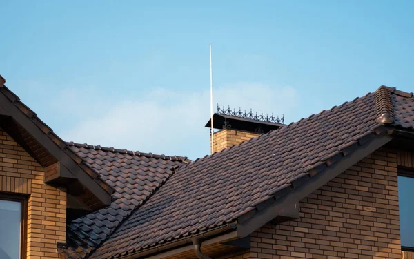 갈색의 천연 타일 지붕. 현대적 인 종류의 지붕 재료. 집의 지붕, 푸른 하늘을 배경으로 한 천연 지붕 타일. 건축. — 스톡 사진