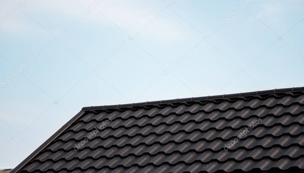 Brown metal tile roof. Roof metal sheets. Modern types of roofing materials. Roof of the house, metal roof tile against the blue sky. Building.