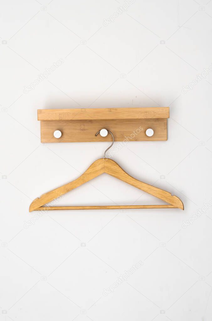 Clothes wooden hanger on a white wall.