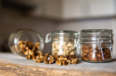 Ceviz bir kavanozdan beyaz şarap masasına saçılmış. Ceviz sağlıklı bir vejetaryen protein besleyici gıdadır. Ceviz çekirdekleri ve eski ahşap cevizler..