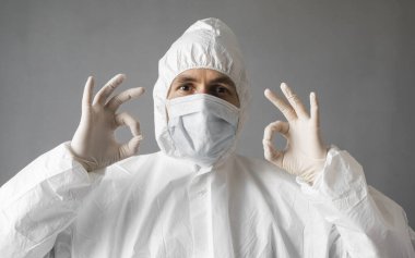 Beyaz koruyucu giysili doktor, tıbbi maske ve lastik eldiven her şeyin yolunda olduğunu gösteriyor. Koronavirüs salgını tehdidi altındayken insanlara yardım etmek. Salgın, Coronavirus covid 19 salgını..
