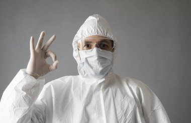 Beyaz koruyucu giysili doktor, tıbbi maske ve lastik eldiven her şeyin yolunda olduğunu gösteriyor. Koronavirüs salgını tehdidi altındayken insanlara yardım etmek. Salgın, Coronavirus covid 19 salgını..
