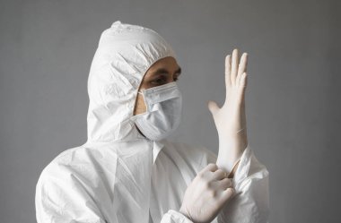 Beyaz koruyucu giysili doktor, tıbbi maske ve lastik eldivenler koronavirüs salgını tehdidi altındayken insanlara yardım etmeye hazır. Salgın, Coronavirus covid 19 salgını. Solunum cihazındaki doktor..