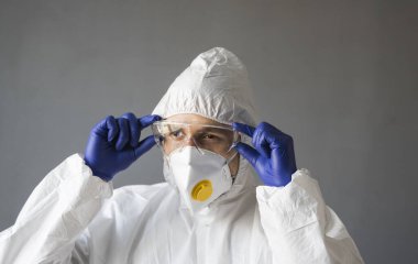 Beyaz koruyucu giysili doktor, tıbbi maske ve lastik eldivenler koronavirüs salgını tehdidi altındayken insanlara yardım etmeye hazır. Salgın, Coronavirus covid 19 salgını. Solunum cihazındaki doktor..