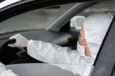 Koruyucu giysili, tıbbi maskeli ve plastik eldivenli bir adam bakteri ve virüsten korunmayı planlıyor. Karantina sırasında koruyucu maske, dünya salgını, covid 19, koronavirüs, enfeksiyon.