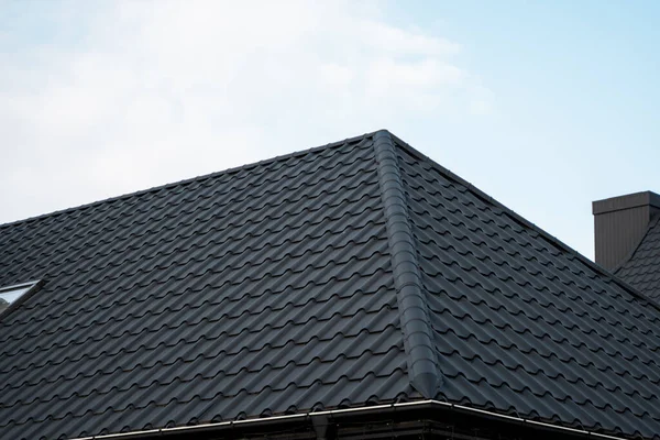 Schwarzes Ziegeldach. Dachbleche. Moderne Arten von Dachmaterialien. Dach des Hauses, Dachziegel aus Metall gegen den blauen Himmel. Bauen. — Stockfoto