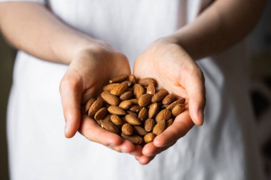 Bir kadının elinde badem. Badem fıstığı sağlıklı bir vejetaryen proteini ve besleyici yemektir. Bir insanın elinde fındık.