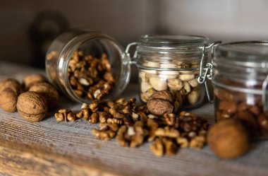 Ceviz, bir kavanozun içindeki beyaz şarap masasına serpilmişti. Ceviz sağlıklı bir vejetaryen protein besleyici gıdadır. Ceviz çekirdekleri ve eski ahşap cevizler..