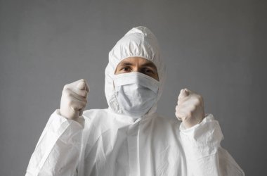 Beyaz koruyucu giysili doktor, tıbbi maske ve lastik eldivenler virüse işaret ediyor. Koronavirüs salgını tehdidi altındayken insanlara yardım etmek. Salgın, Coronavirus covid 19 salgını..