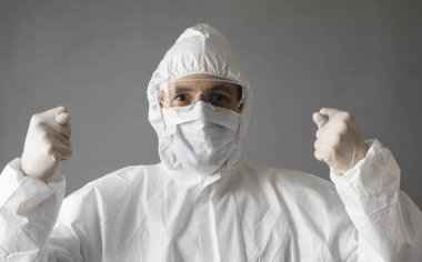 Beyaz koruyucu giysili doktor, tıbbi maske ve lastik eldivenler virüse işaret ediyor. Koronavirüs salgını tehdidi altındayken insanlara yardım etmek. Salgın, Coronavirus covid 19 salgını..