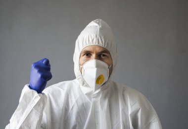 Beyaz koruyucu giysili doktor, tıbbi maske ve lastik eldivenler virüse işaret ediyor. Koronavirüs salgını tehdidi altındayken insanlara yardım etmek. Salgın, Coronavirus covid 19 salgını..