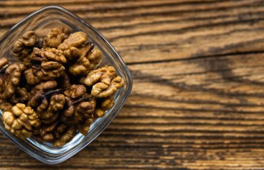 Arka plan olarak eski ahşap bir masada küçük bir tabakta ceviz. Ceviz sağlıklı bir vejetaryen protein besleyici gıdadır. Doğal çerezler.