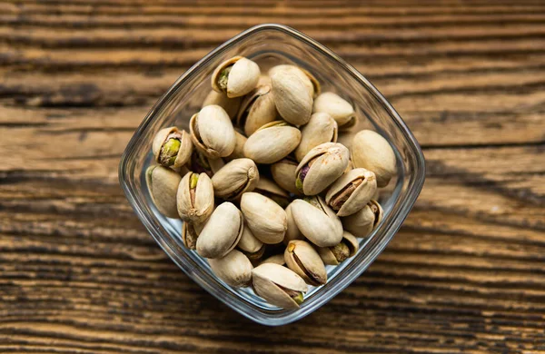 Pistazien in einem kleinen Teller auf einem alten Holztisch als Hintergrund mit Kopierraum. Pistazie ist eine gesunde vegetarische Proteinnahrung. Natürliche Nüsse Snacks. — Stockfoto