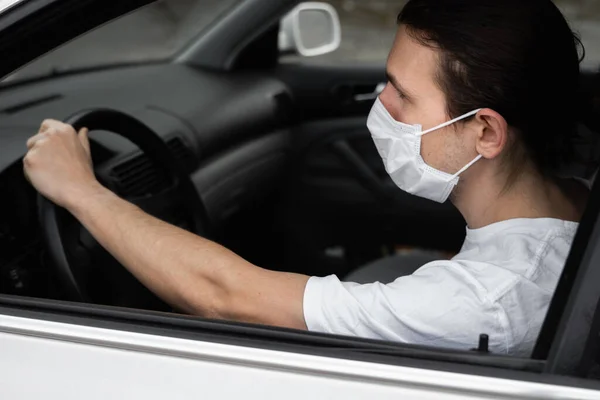 細菌やウイルスから身を守るために保護医療マスクの男は車を運転する予定です。流行、隔離、世界的なパンデミック、 covid 19 、コロナウイルス、感染中の保護マスク. — ストック写真