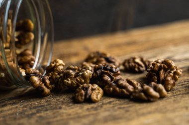 Ceviz, bir kavanozun içindeki ahşap şarap masasına saçılmış. Ceviz sağlıklı bir vejetaryen protein besleyici gıdadır. Ceviz çekirdekleri ve eski ahşap cevizler..