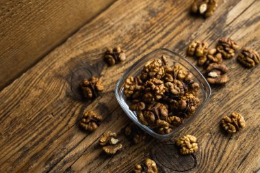 Ahşap bir masanın üzerinde duran kabuklu cevizlerle saçılmış bir tabakta ceviz. Ceviz sağlıklı bir vejetaryen protein besleyici gıdadır. Köhne odunda ceviz.