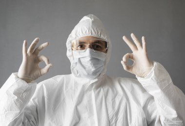 Beyaz koruyucu giysili doktor, tıbbi maske ve lastik eldiven her şeyin yolunda olduğunu gösteriyor. Koronavirüs salgını tehdidi altındayken insanlara yardım etmek. Salgın, Coronavirus covid 19 salgını..
